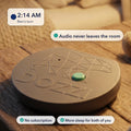 The Dozzi Base, a small round device with an embossed bear logo, on a wooden table in a warmly lit nursery